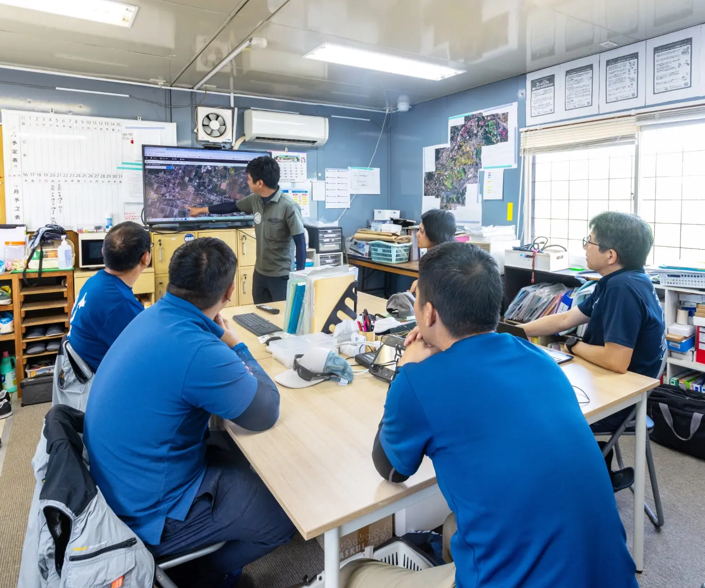 会議室で画面を見ながら話し合うスタッフたち