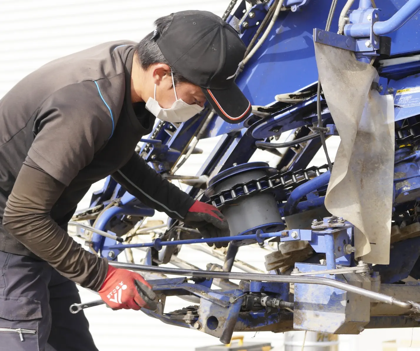 農機具を整備するスタッフが工具で調整を行う様子