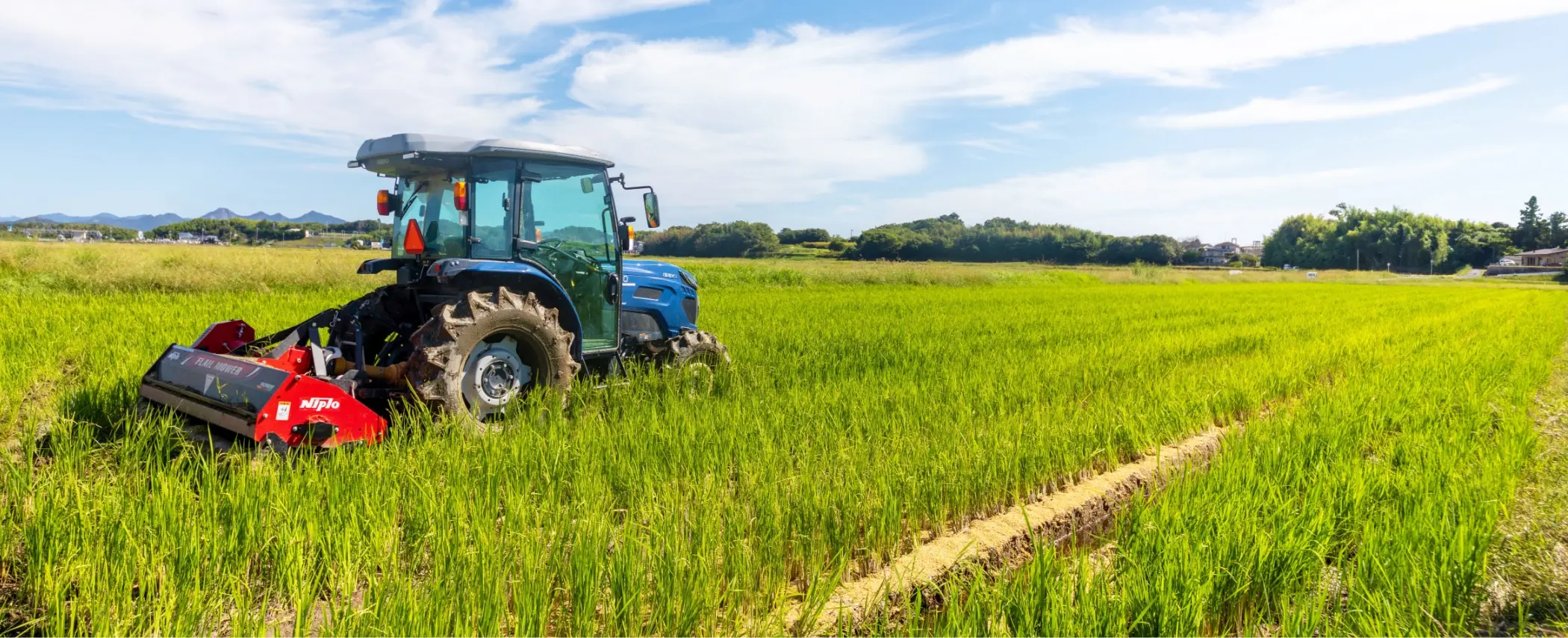 緑の田んぼの中でトラクターが作業をしている様子
