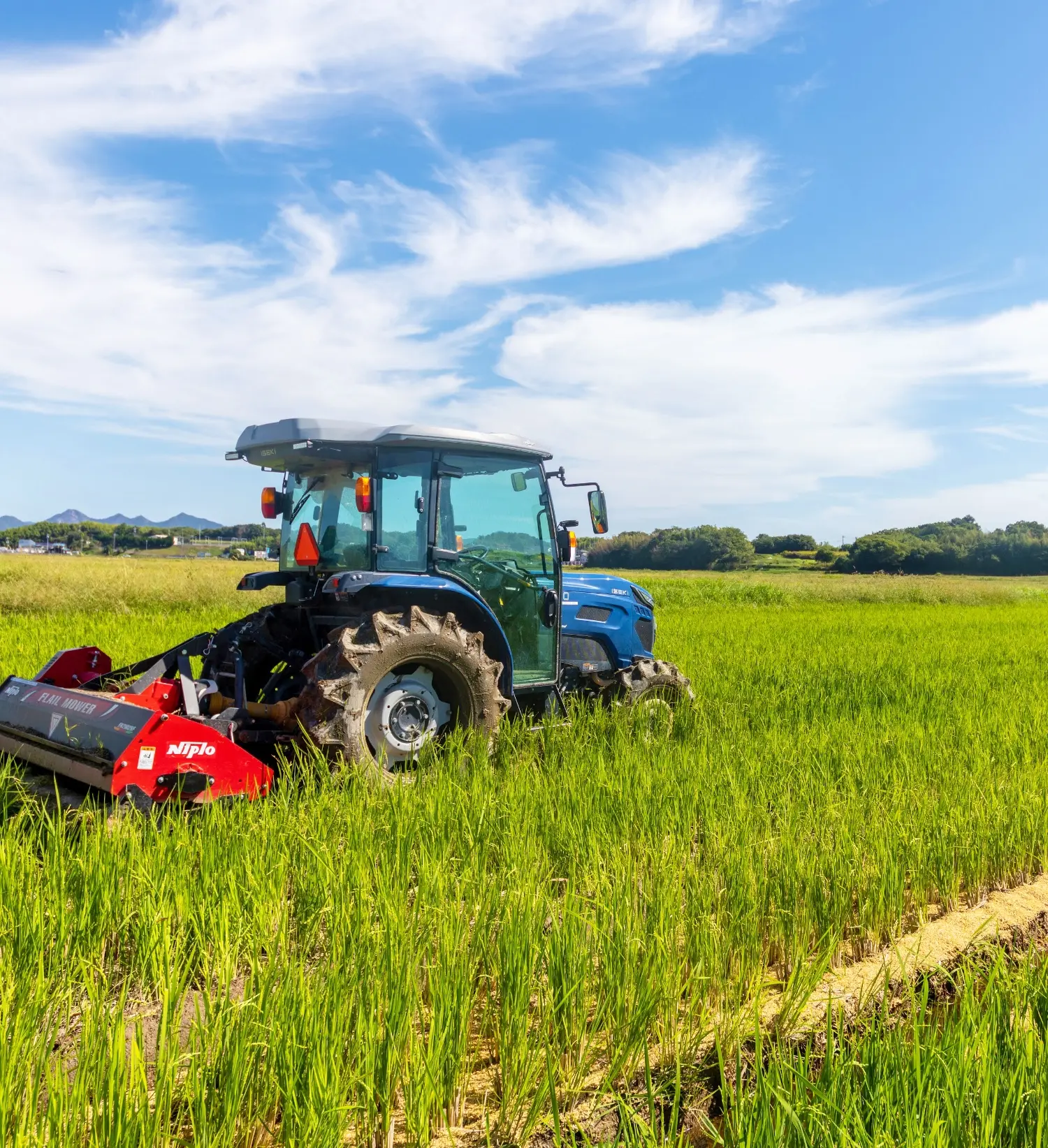 緑の田んぼの中でトラクターが作業をしている様子